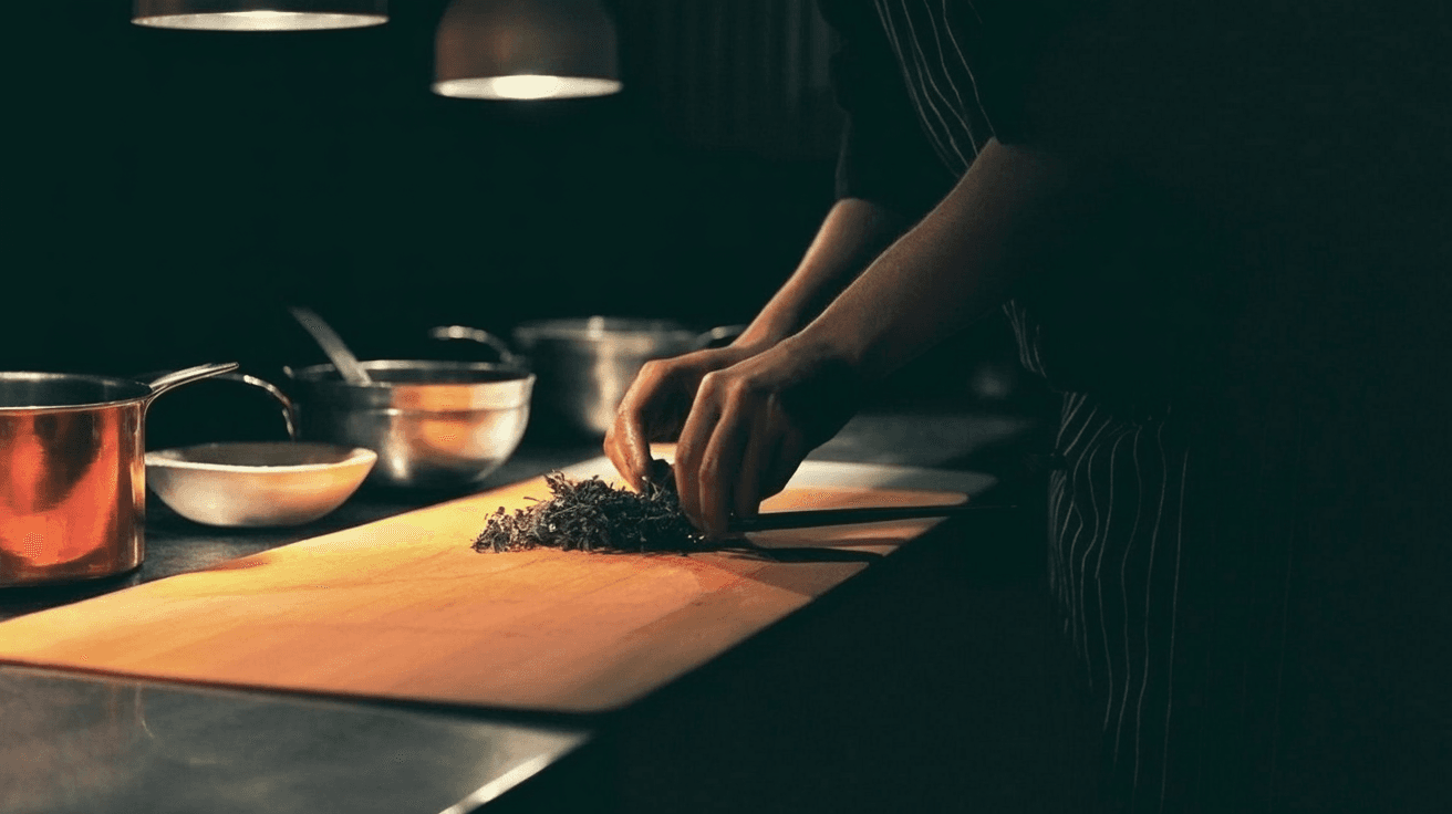 Hands working mise en place, copper pots, warm task lighting